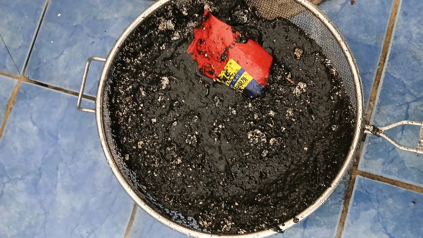 거름망에 걸러낸 검은 슬러지와 세제 포장지 조각